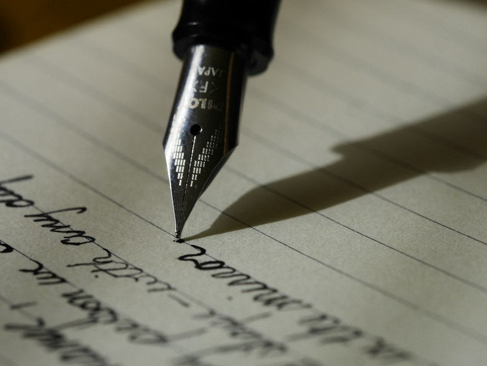 Editor writing thoughtful prose with pen, journal, and warm coffee